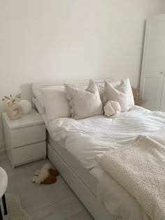 a bed with white sheets and pillows on top of it next to a night stand