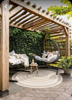 an outdoor area with a swing chair, table and potted plants on the ground