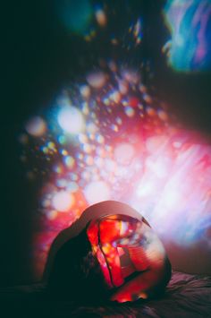 a person laying on a bed in front of a colorful light