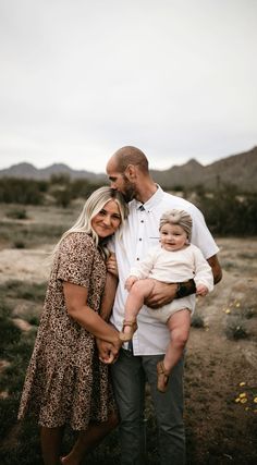 a man and woman holding a baby in the desert