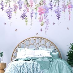 a bed sitting under a purple flower covered wall next to a plant filled with flowers