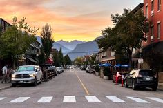 cars parked on the side of a street with mountains in the background