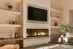 a living room filled with furniture and a flat screen tv mounted on the wall above a fire place