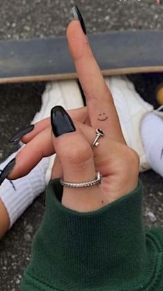 a person with their fingers in the shape of a peace sign and a skateboard behind them