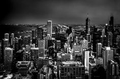 black and white photo of the city skyline at night with lights in the skyscrapers