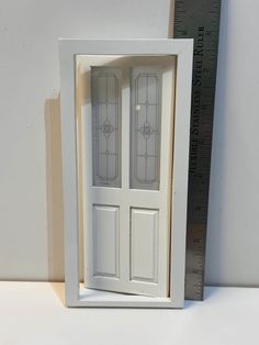 a white door with two glass panels on the front and side, next to a ruler