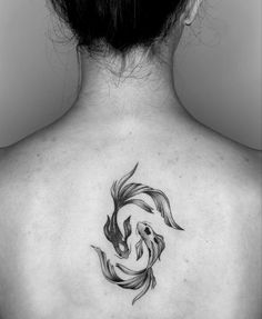 a black and white photo of a woman's back with a fish tattoo on it