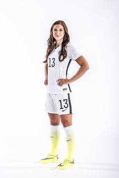 a female soccer player is posing for a photo wearing her uniform and yellow socks with the number 13 on it