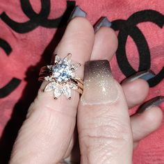 a woman's hand holding an engagement ring with two diamonds on the top and one diamond in the middle