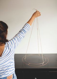 a woman is holding strings in front of a black table with an object on it