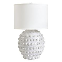 a white ceramic lamp with a white shade on it's base and a white fabric lampshade