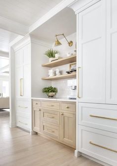 a kitchen with white cabinets and gold handles on the doors, along with wooden flooring