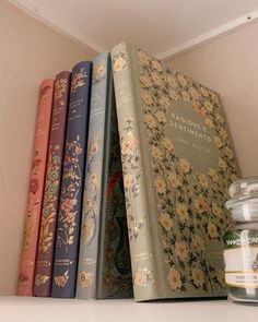 some books are lined up on a shelf next to a jar and glass jar filled with honey