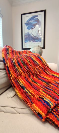 an orange and blue blanket sitting on top of a white couch