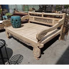 a wooden bench sitting next to a blue vase on top of a patio table in front of other outdoor furniture