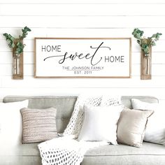 a living room filled with furniture and pillows on top of a wooden sign that says home sweet home