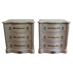 two white nightstands with gold handles on each side and one has a drawer in the middle