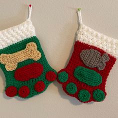 two crocheted christmas stockings with dogs on them hanging from the wall, one has a bone in it