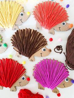 hedgehogs made out of paper and yarn on a white surface with pom poms