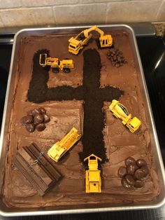 a cake decorated with construction vehicles and dirt in the shape of a man's cross