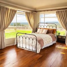 a bedroom with wooden floors and large windows