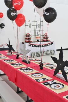 the table is set up with black and white balloons, star - shaped paper stars, and other decorations