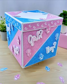 a pink and blue box sitting on top of a table next to a potted plant