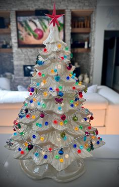 a glass christmas tree with multicolored ornaments