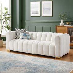 a white couch sitting on top of a wooden floor in a living room next to a green wall