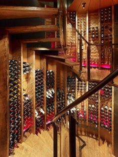 a spiral stair case filled with lots of wine bottles next to a wooden handrail