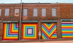 a colorful mural on the side of a brick building in front of a garage door