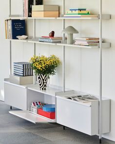 a white shelf with books and flowers on it