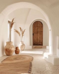 two vases sitting on the floor in front of a doorway with an archway leading to another room