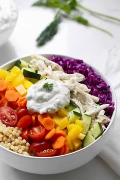 a white bowl filled with lots of veggies and some kind of dip in it