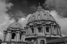 black and white photograph of an old building with two domes on the top, against a cloudy sky