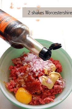 a bowl filled with meat and onions next to a bottle