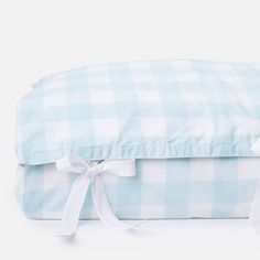 a blue and white checkered pillow sitting on top of a bed with a bow