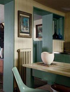 a dining room table with chairs and pictures hanging on the wall above it, in front of a doorway