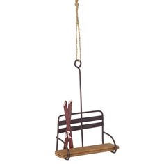 a wooden bench hanging from a rope with scissors on it's back and two pairs of skis attached to the seat