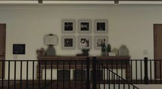 a living room filled with furniture and pictures on the wall above a wooden fireplace mantel