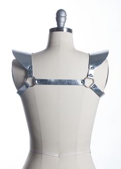 This chestpiece shoulder harness adds drama and impact to any outfit. Epaulette shoulder "wing" details. Show them you mean business! This piece works especially well with dresses and flowing tops that don't have a defined waistline. Silver toned nickel-plated steel hardware. Shown in silver metallic leather (silver leather is now lined and stitched!). Also available in black leather, black vegan leather, and PVC.Buckles in front across chest. All pieces are MADE TO ORDER, standard sizes XS-4XL. Gothic Fitted Harness With Adjustable Straps, Fitted Strapped Harness For Party, Gothic Fitted Harness For Party, Fitted Belt Harness For Cosplay, Fitted Harness With Belt For Cosplay, Gothic Party Harness With Straps, Punk Style Harness With Adjustable Straps For Party, Punk Style Party Harness With Adjustable Straps, Edgy Party Harness With Straps