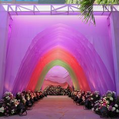 an archway decorated with flowers and greenery in the shape of a rainbow colored arch