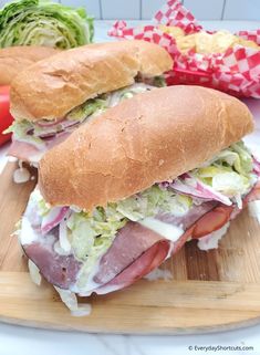 a sandwich with meat, lettuce and tomatoes on a cutting board