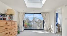 an empty room with a large window, dresser and chest of drawers in front of it