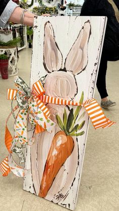 a wooden sign with a carrot painted on it's side and ribbon tied around the front