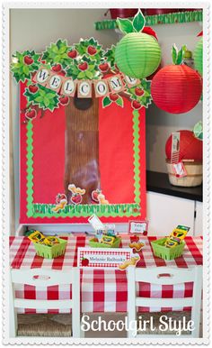 a red and white checkered table cloth with apples on it in front of a bulletin board