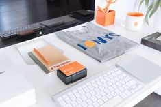 an office desk with a computer, keyboard and orange accessories on it in front of a monitor