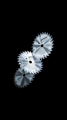 two circular saws sitting next to each other on a black surface with one being cut in half