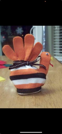 an orange and white knitted bird sitting on top of a wooden table