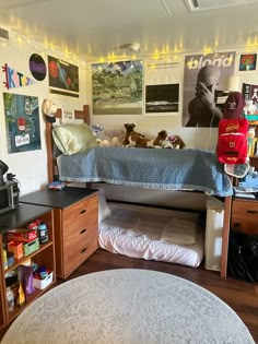 a dorm room with bunk beds, desks and other items on the wall behind it